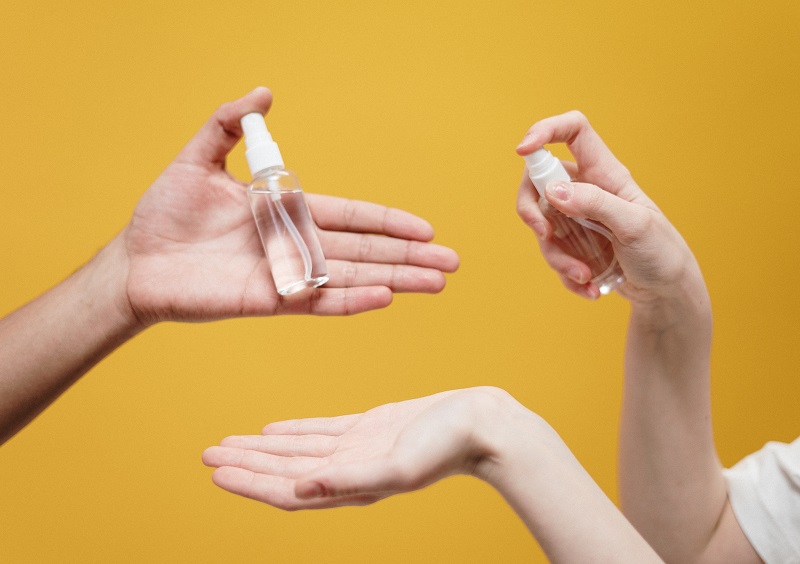 Close up of people spraying hand sanitizer