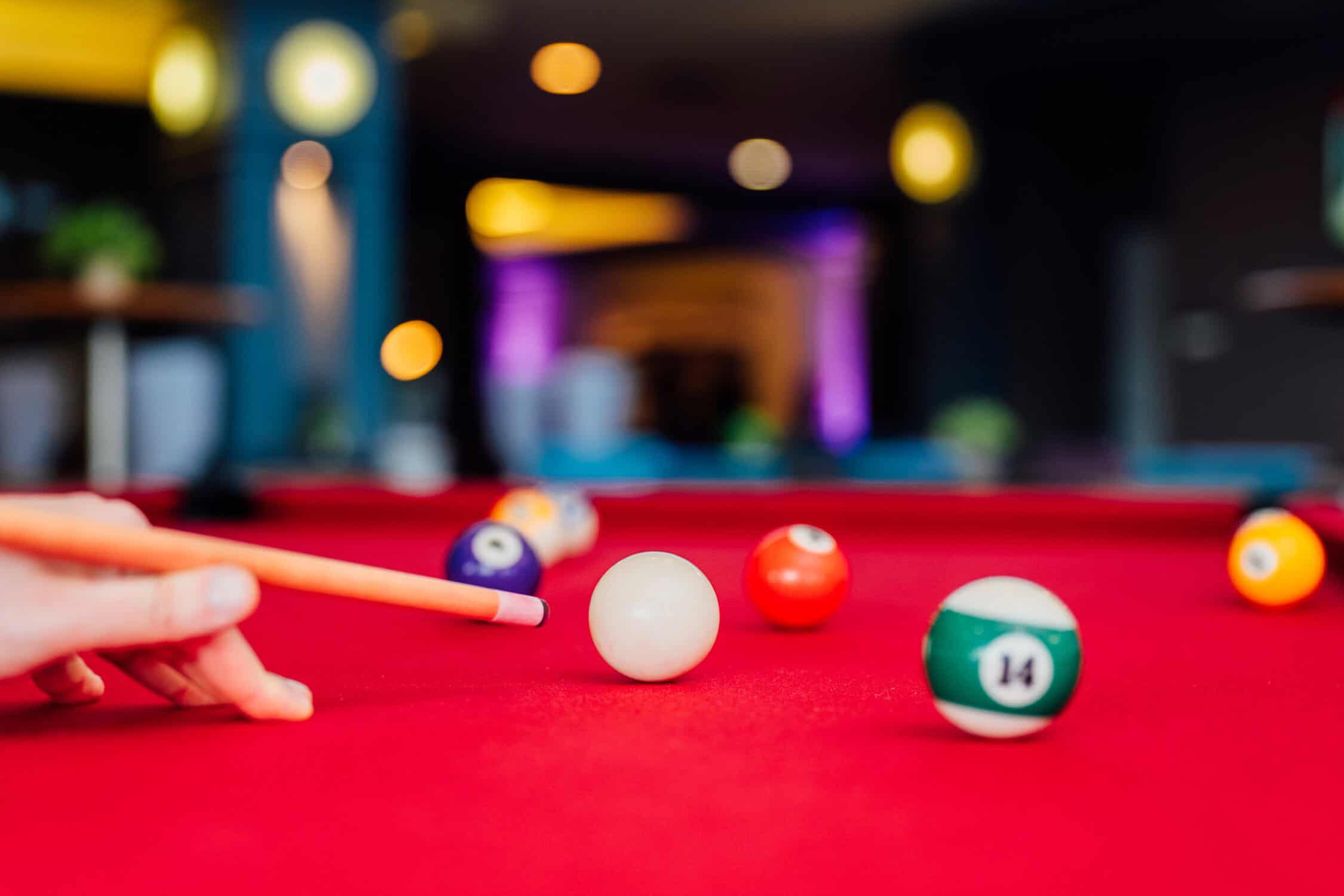 picture of someone playing pool on a red pool table