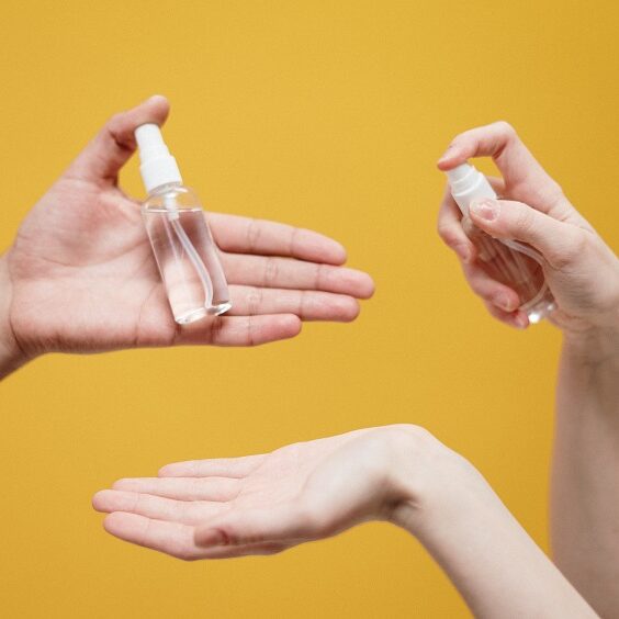 Close up of people spraying hand sanitizer